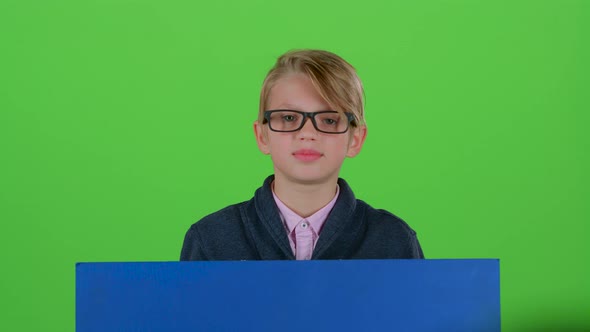 Child Boy in Glasses Emerges From Behind the Board and Waving on a Green Screen