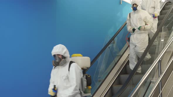 Disinfection Service on Escalator in the Building Team of Sanitation Workers in Suit Using Pressure