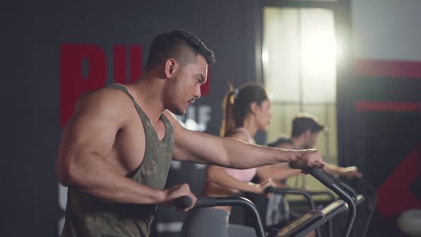 Group of sport man and woman sitting on stationary bicycles or exercise bikes machine in gym stadium