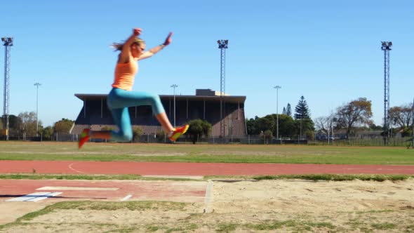 Side view of Caucasian female athlete practicing long jump at sports venue 4k