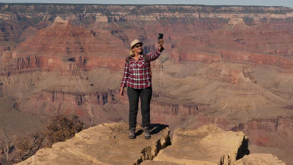 Hiker Woman Takes Selfie On Her Phone Standing On Edge Of Cliff In Grand Canyon