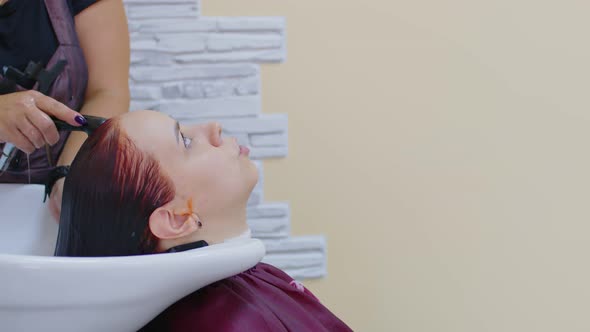 Young Woman with Hairdresser Washing Head at Hair Salon After Coloring the Hair