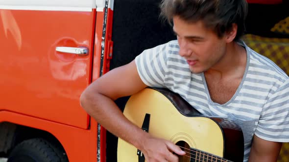 Man playing guitar in camper van 4k