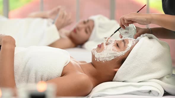 Beautiful Asian woman enjoying applying white mud to her face. at a luxury spa resort