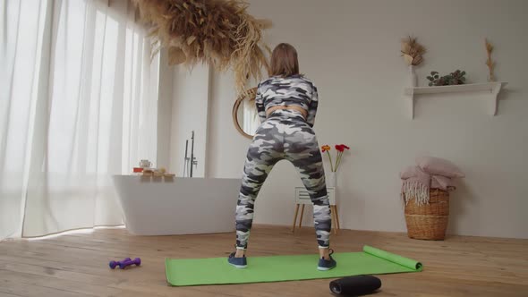 Rear View of Active Sporty Fit Woman Performing Squat Exercise in Domestic Room