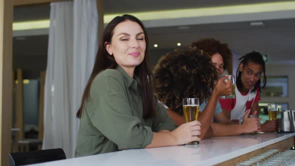 Diverse group of happy friends drinking beers and smiling at a bar