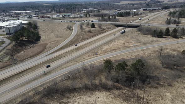 Aerial view of rural interstate and highway interchange. Forest and mountains in distance.