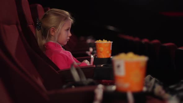 Little Girl Alone in the Cinema Looks at the Cinema Screen