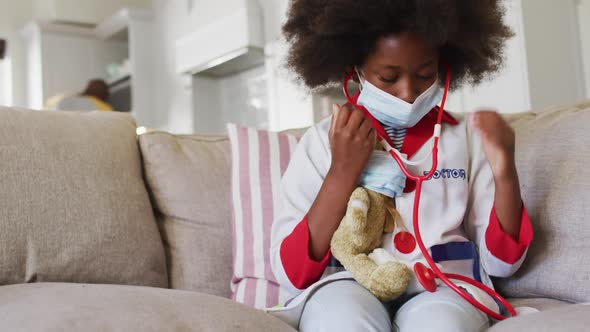 African american girl playing doctor and patient with her teddy bear