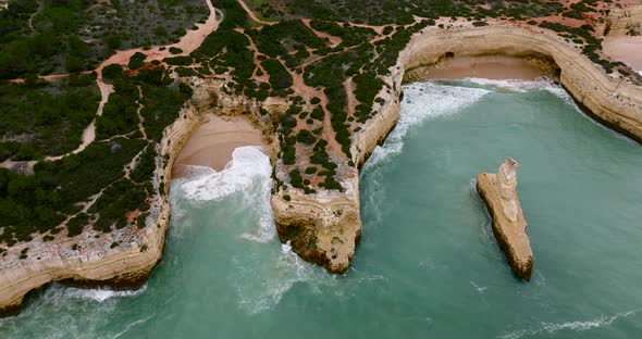 Aerial footage on a moody day as the ocean is hitting the beaches of the Algarve coast