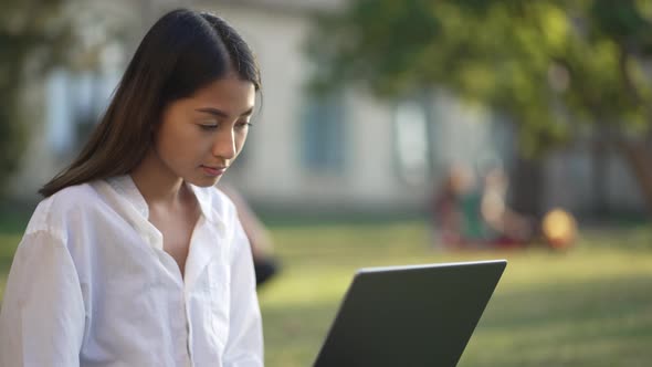 Cute Asian Girl Student Studying on Campus Lawn