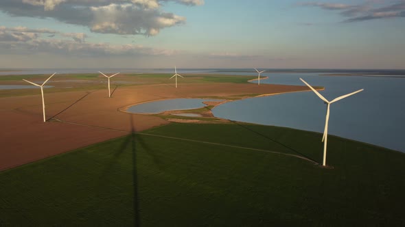 Aerial View of Wind Turbines and Agriculture Field Near the Sea at Sunset