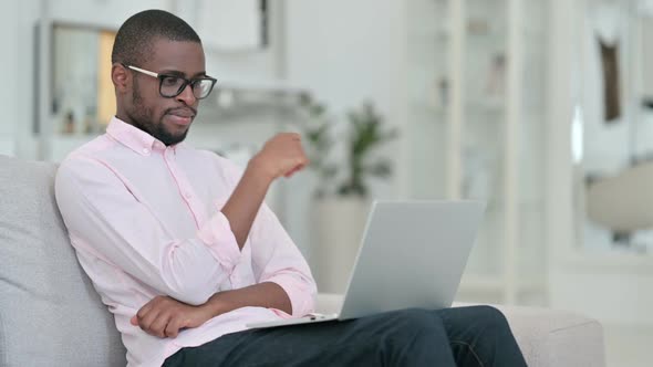 Pensive African Man Thinking and Working on Laptop at Home