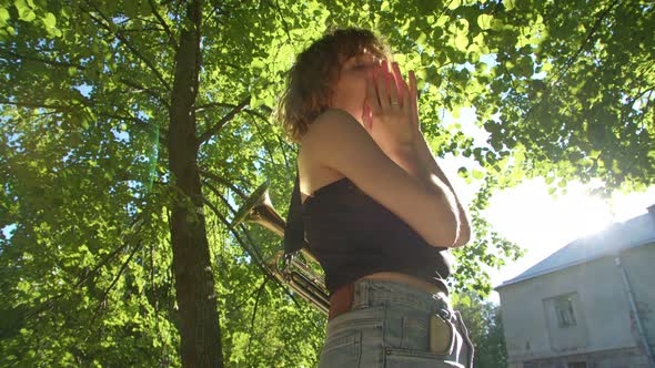 Woman Standing Prays Against the Background of a Green Tree and in Gratitude Raises Her Hands Up