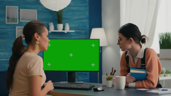 Two Women Looking at Computer with Mock Up Green Screen