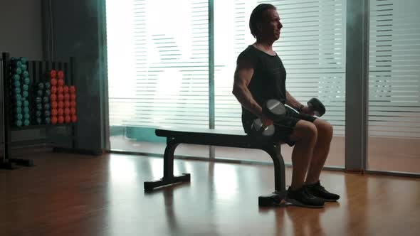 Mature Man Lifting Up Big Dumbbells to Pump Up His Biceps