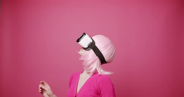 Woman Uses a Virtual Reality Glasses on Isolated Pink Background