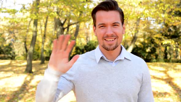 Young Man Stands in the Woods, Is Cheerful and Waves