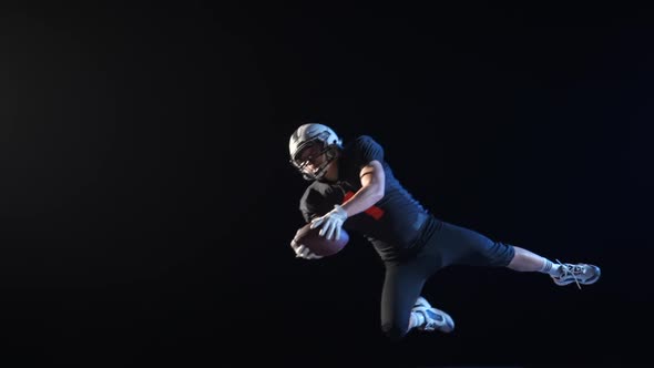 American Football Player Wearing Uniform Pads and Helmet Jumping Catching Pass and Diving to Ground