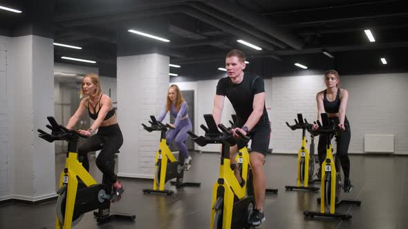 Group of People is Engaged in a Modern Exercise Bikes Performs Aerobic Endurance Training on the