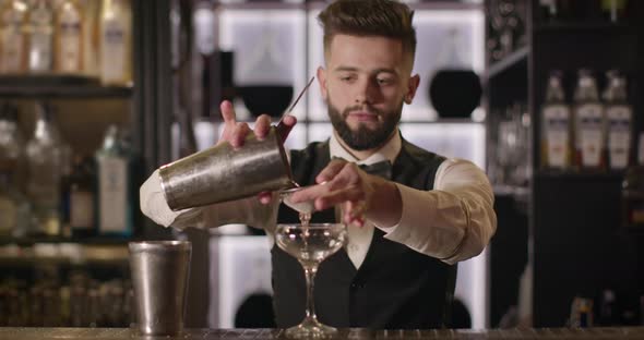 Bartender Is Pouring the Alcohol From the Shaker Through a Cocktail Strainer Into the Glass