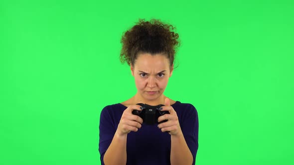 Portrait of Curly Woman Playing a Video Game Using a Wireless Controller with Joy. Green Screen