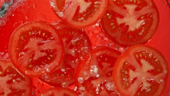 Super Slow Motion Shot of Tomato Slices Falling Into Water on Red Background at 1000Fps.