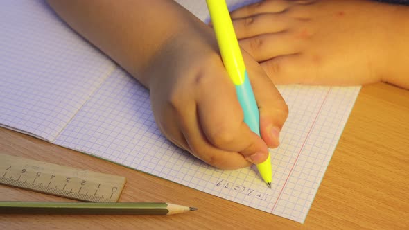 A Closeup of the Student's Hands Solves Mathematical Examples in a Notebook