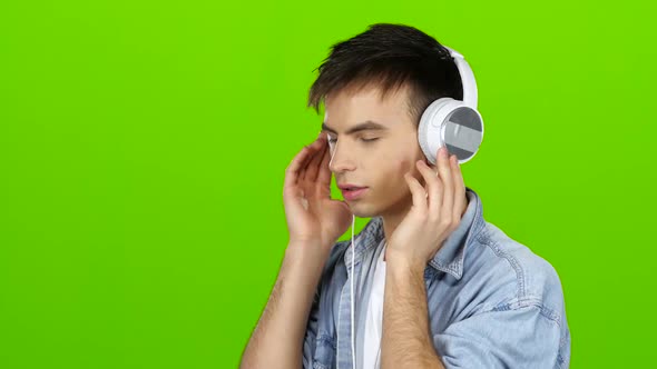 Guy Listens To the Music in the Headphones and Adjusts To the Positive. Green Screen