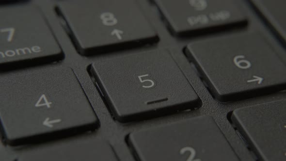 The Finger Presses a Button with a Number on the Keyboard