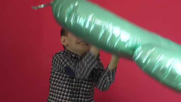The child celebrates his 8th birthday. A cheerful Caucasian boy throws up an inflatable balloon in t