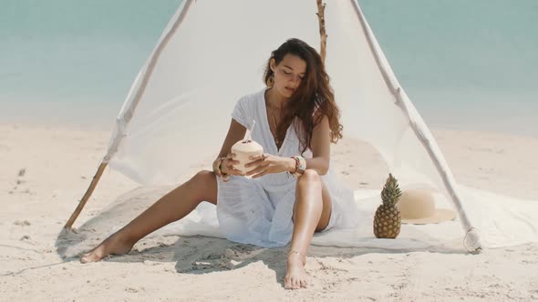 Woman Drinking Coconut Juice While Relaxing on the Beach