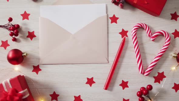 Video of christmas decorations with presents and envelope on wooden background