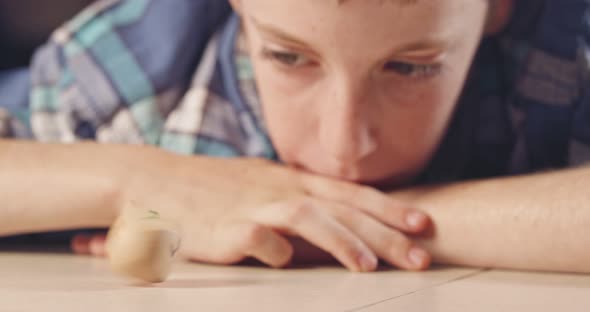 Close up shot of a boy spinning a Hanukka dreidel on the floor