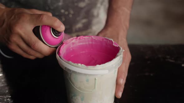 Man works with paint in his trowel. Mixes paint with polymer.