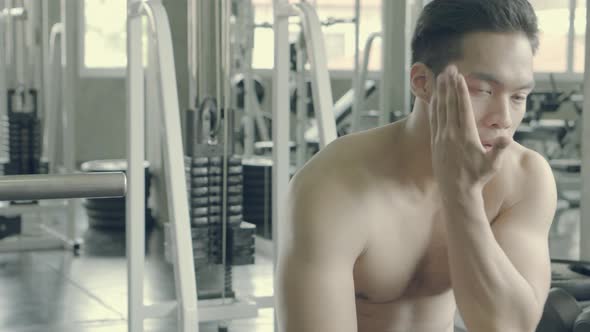 Handsome asian man have muscular after workout with tired and exhaustion in the gym.
