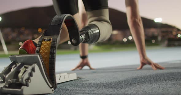 Low section of caucasian disabled male athlete with running blade getting ready to start a run