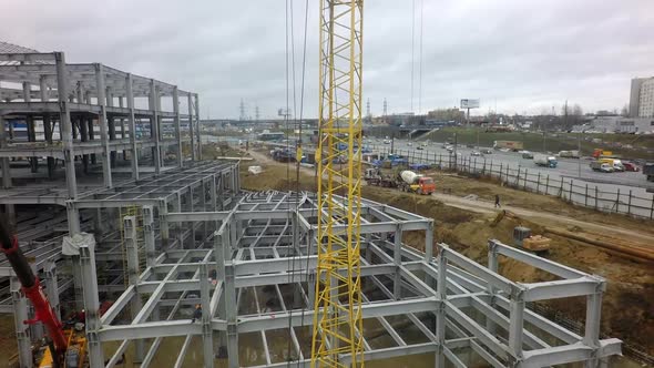 A vertical inspection of a construction crane against the building frame and a busy highway