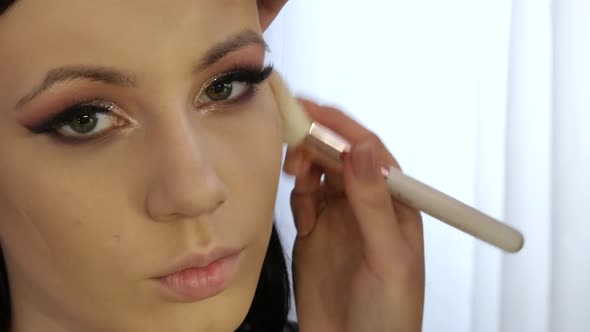 A Professional Makeup Artist Applies Eyeshadow with a Special Brush in a Makeup Studio
