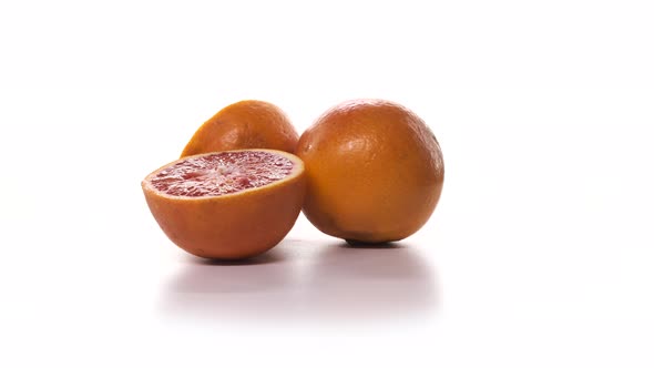 Two Fresh Cutted Red Oranges are Spinning on White Background