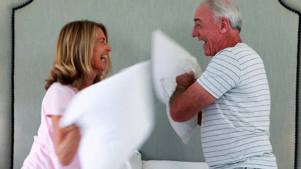 Laughing couple having pillow fight on bed