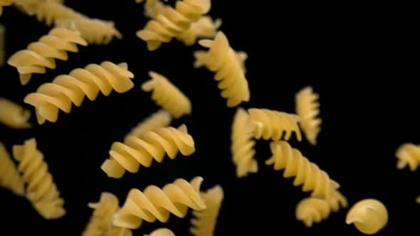 Closeup of the Dry Pasta Fusili Flying Diagonally on a Black Background