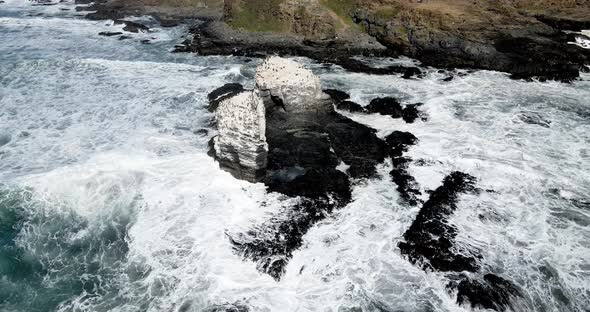 Aerial orbit of Punta de Lobos rocks with birds on their tops on a sunny day.