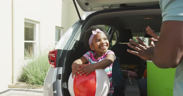 Happy african american family packing car with beach balls on holiday