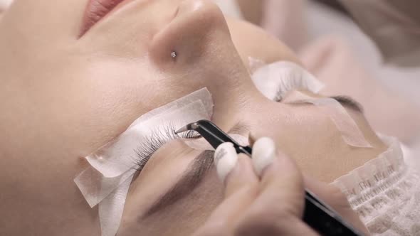 Lash Maker Performing Eyelash Extension Procedure for Young Woman.