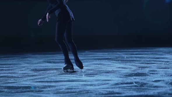 Figure Skating Lady is Skating on Ice Rink Training at Night in the Rays of Blue Light