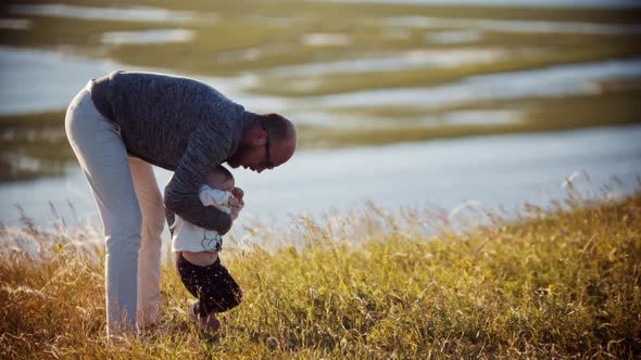 Young Father with His Baby Daughter on the Field - Teaching His Daughter How To Walk