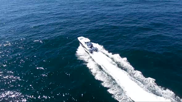 Top down view of boat riding in the open ocean with blue water and sunny skies