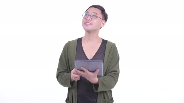 Happy Japanese Man with Eyeglasses Thinking While Using Digital Tablet