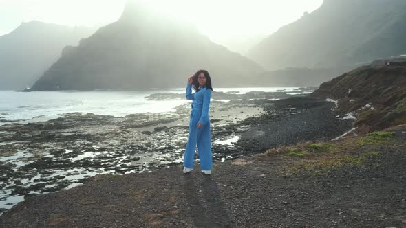 A Woman Walks Next to the Ocean Enjoying the Calm Scenery Against the Background of the Volcanic